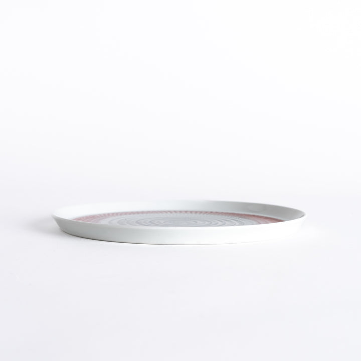 Side view of the plate, showcasing its sleek profile and the vibrant red spiral design.