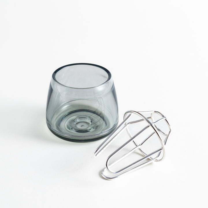 Glass vase with silver frame lying beside it, showing both components separately.