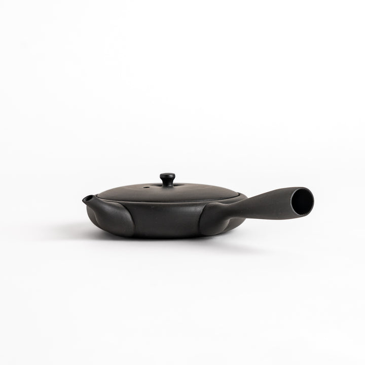 Sleek black teapot with a flat design, side handle, and minimalist aesthetic, perfect for serving tea with elegance and simplicity.