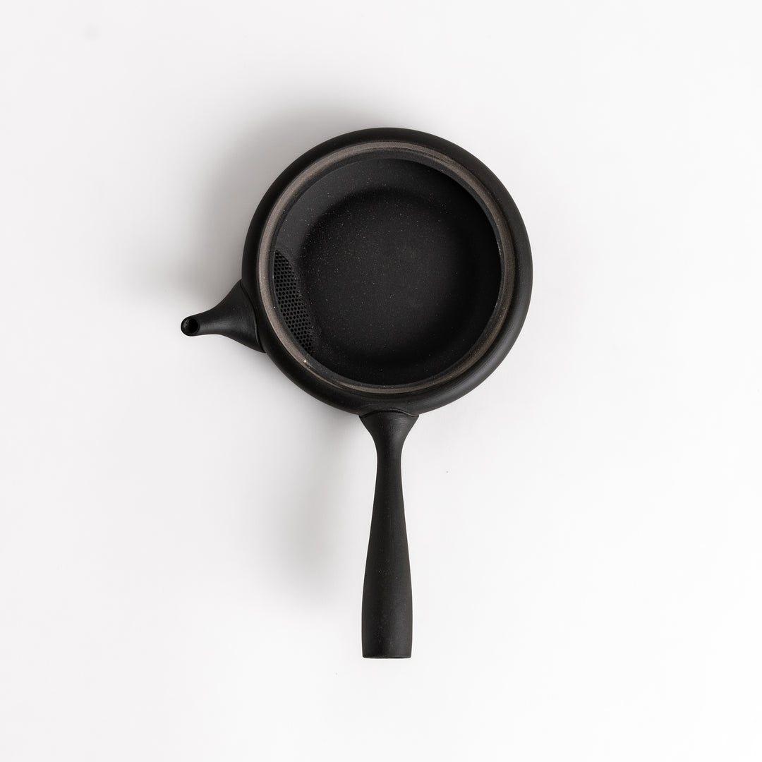 Sleek black teapot with a flat design, side handle, and minimalist aesthetic, perfect for serving tea with elegance and simplicity.