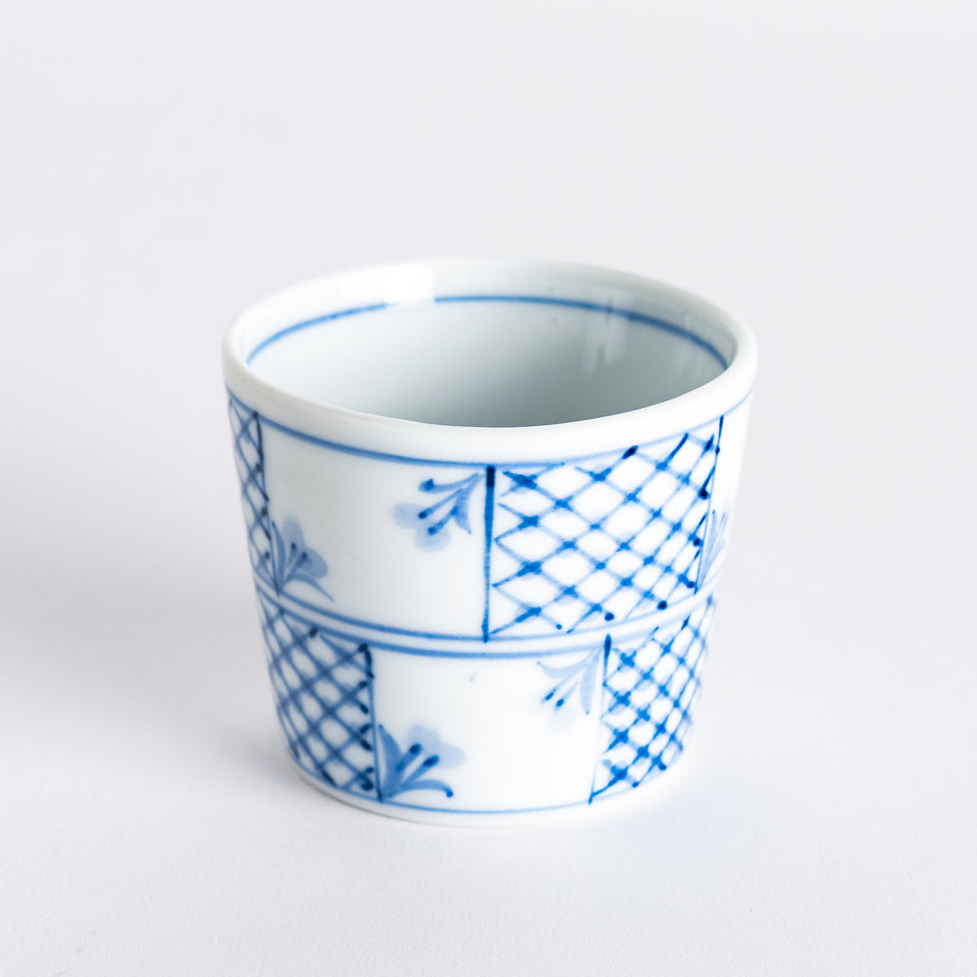 Close-up of the rim of a small condiment bowl, highlighting its intricate blue floral and checkered details.