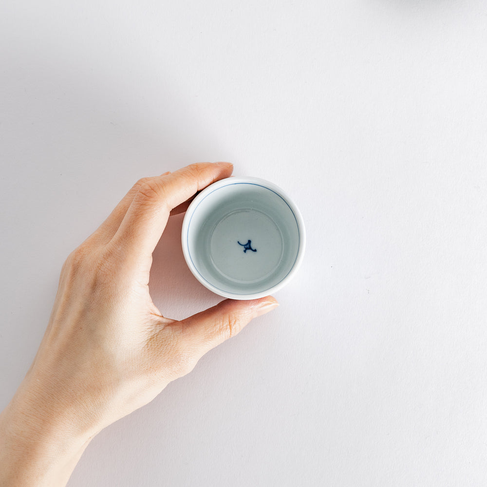 A hand holds a small condiment bowl, showcasing its blue and white floral design, ideal for any dining table.