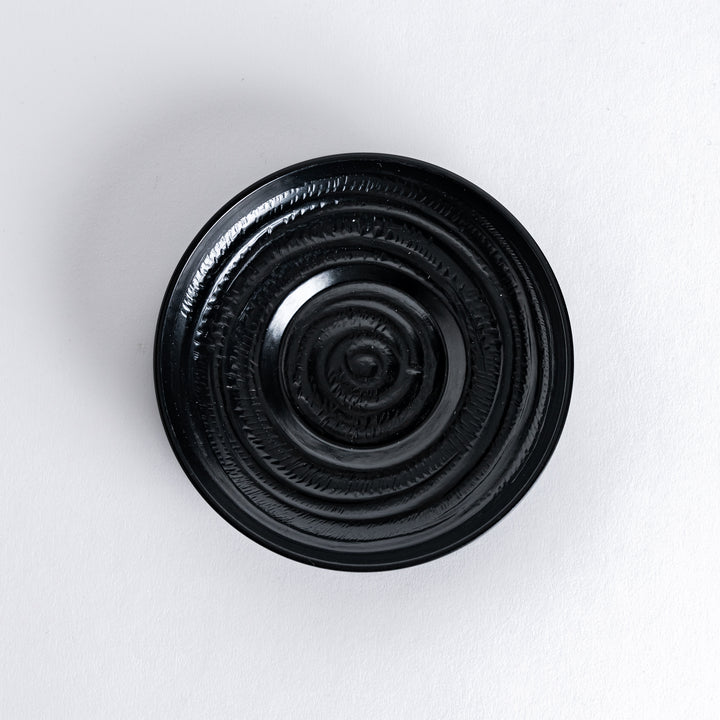 Close-up of the black saucer, showcasing its smooth surface and elegant rim.