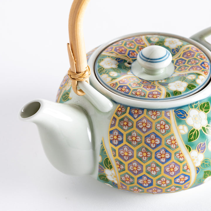 Close-up of the teapot, highlighting the bamboo handle and floral design with a pink and green color scheme.