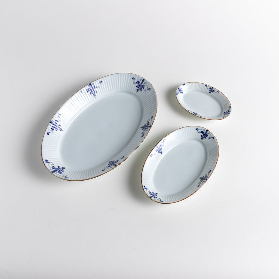 Three-piece oval plate set with a ridged design and floral motifs in blue, featuring a large, medium, and small plate arranged together.