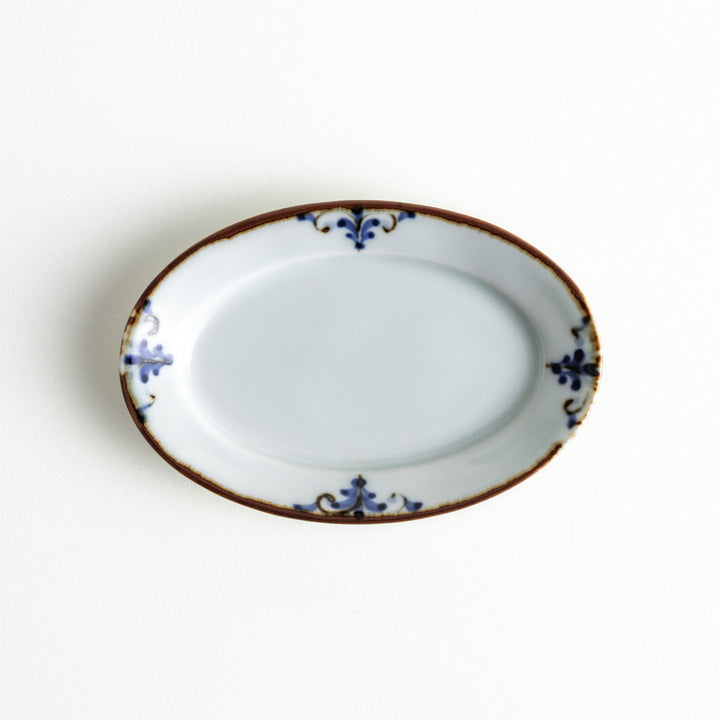 A single oval plate featuring a blue floral leaf design around the edges, showcasing its elegant shape and detailed decoration.