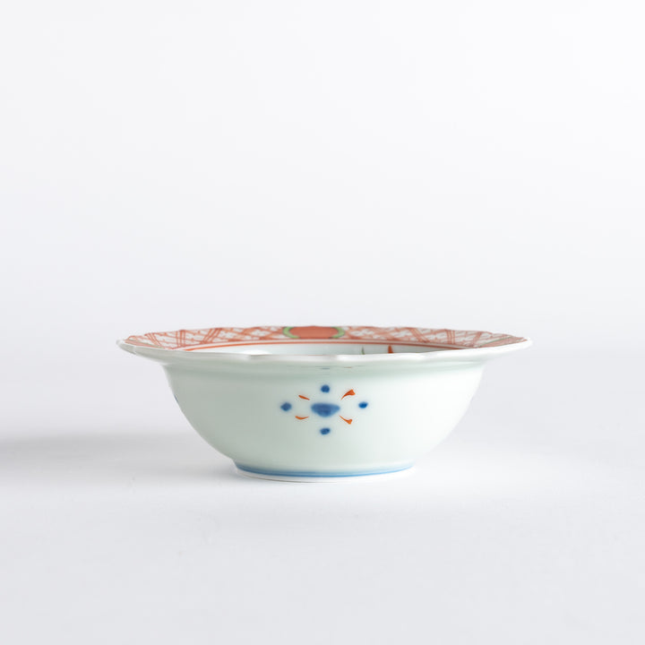 A dessert bowl with bold red and green designs around the rim, with a large blue kanji character in the center representing "fortune."