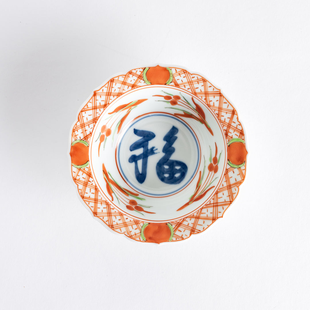 A dessert bowl with bold red and green designs around the rim, with a large blue kanji character in the center representing "fortune."