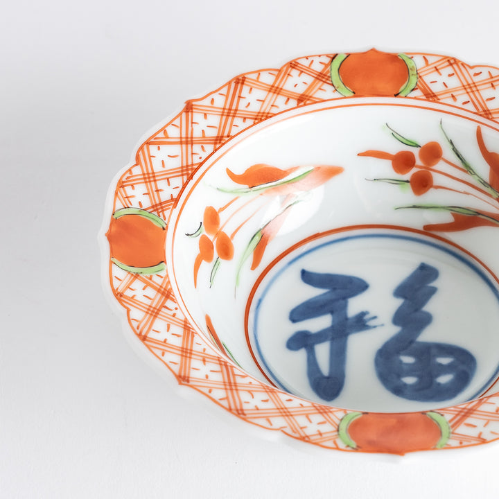 A dessert bowl with bold red and green designs around the rim, with a large blue kanji character in the center representing "fortune."