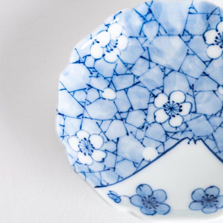 Close-up of the top of the round dish, showing intricate blue patterns of blossoms and mountains, emphasizing the fine details.