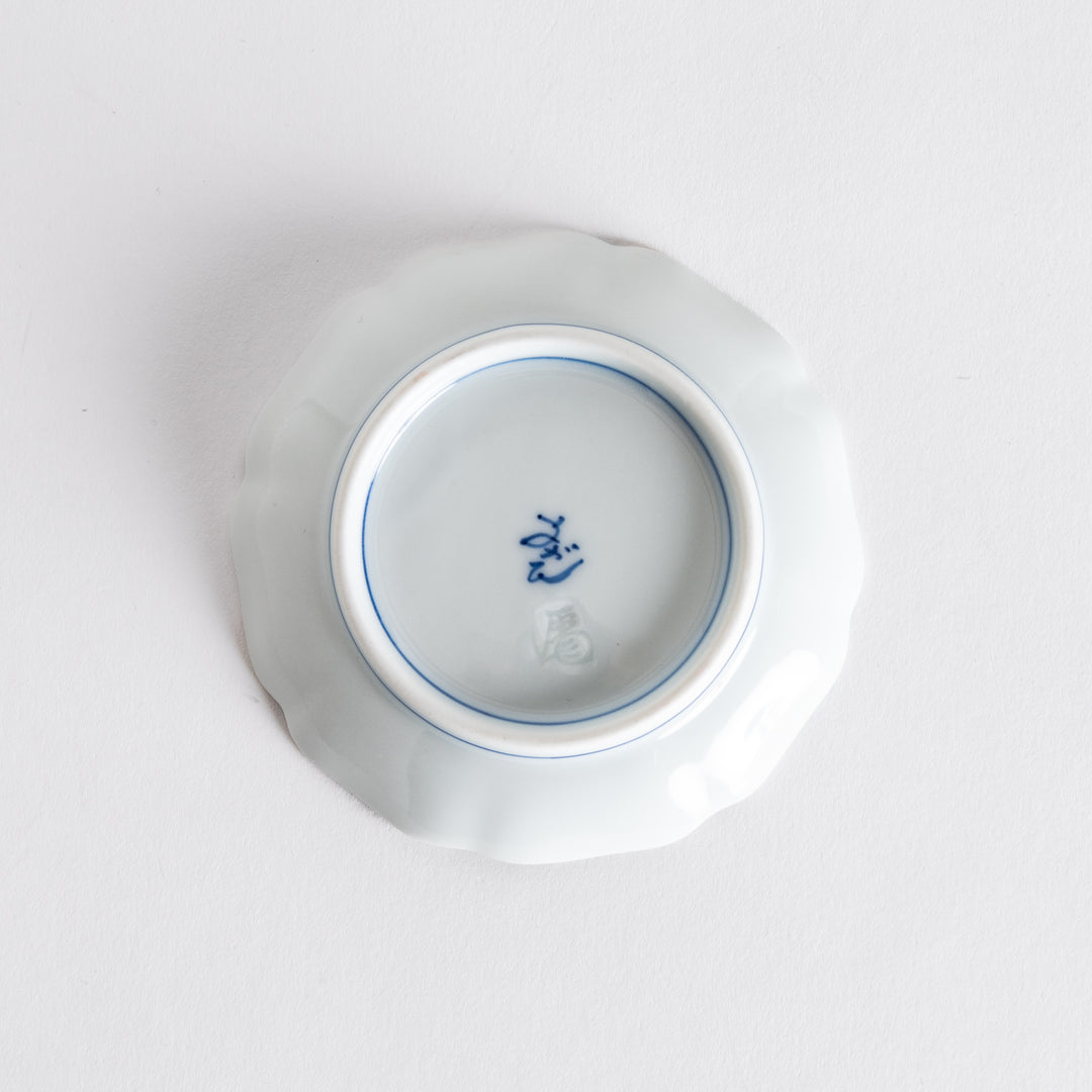 Bottom view of the round dish, revealing the craftsmanship with a signature mark in blue on a pristine white base.