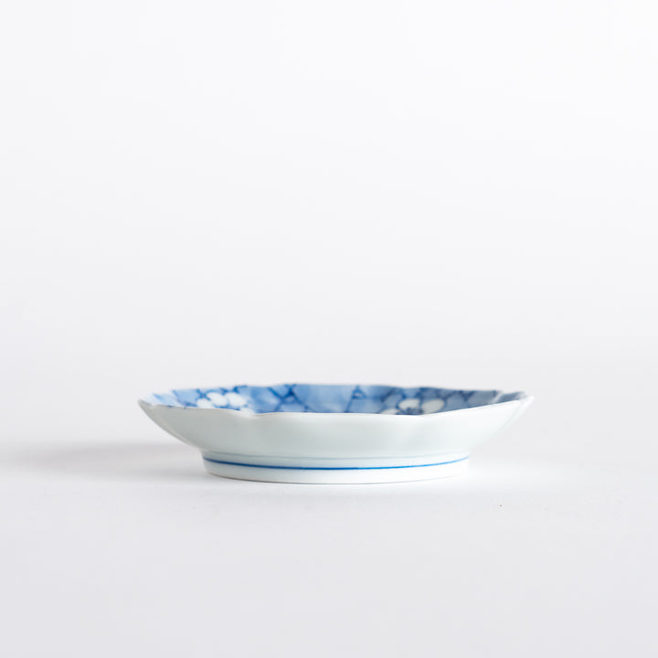 Side view of the round dish displaying its elegant curves, with a soft blue design and a refined finish on a white background.