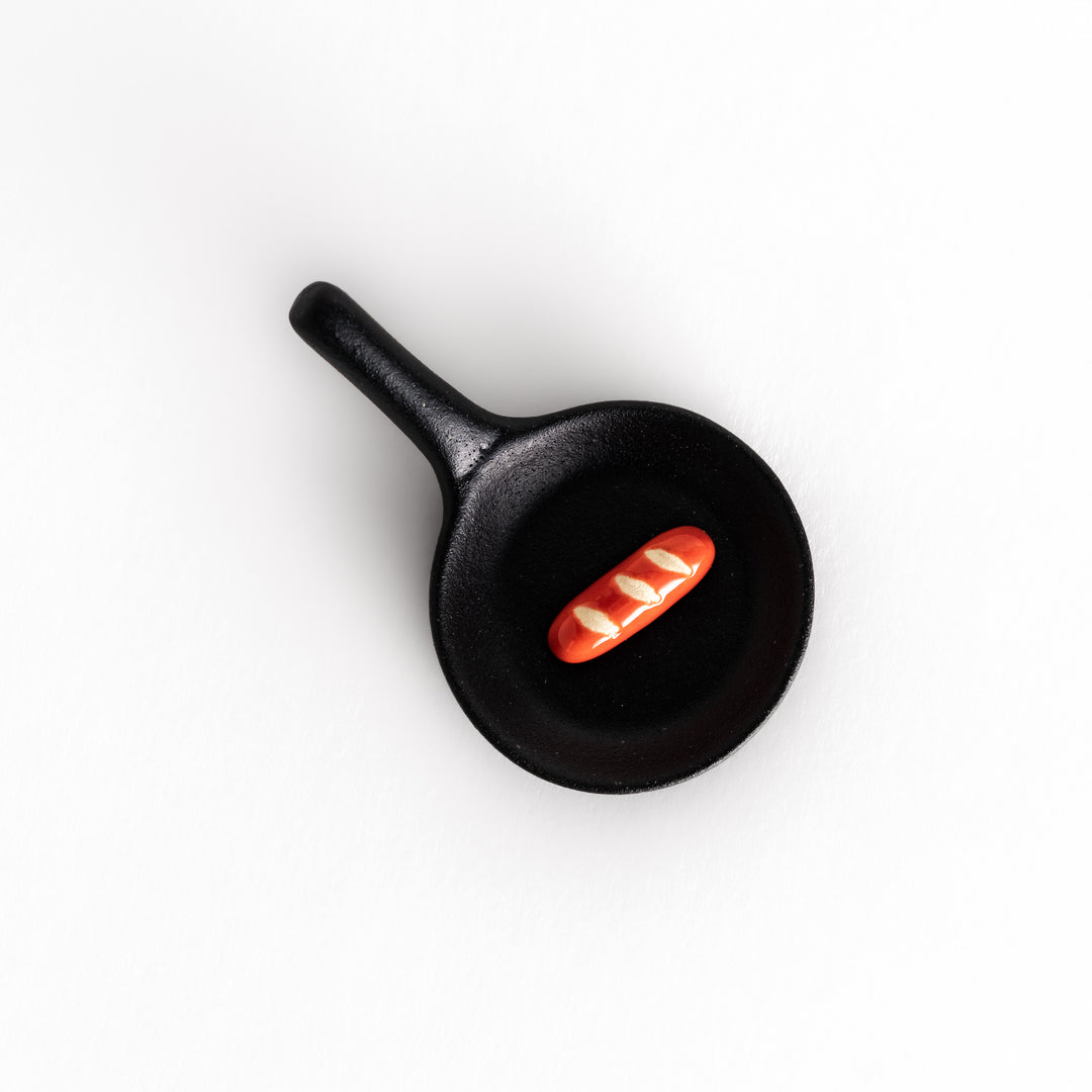 Top-down view of the black frying pan-shaped chopstick rest, emphasizing its unique design and compact size.