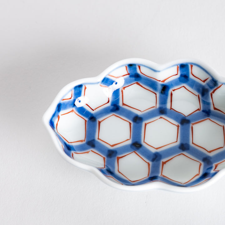 Close-up of the interior of a decorative sauce dish, showcasing the vibrant blue and red hexagonal pattern.