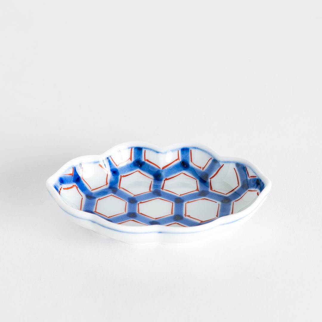 Side view of a decorative sauce dish displaying its elegant shape and intricate blue and red hexagonal pattern.