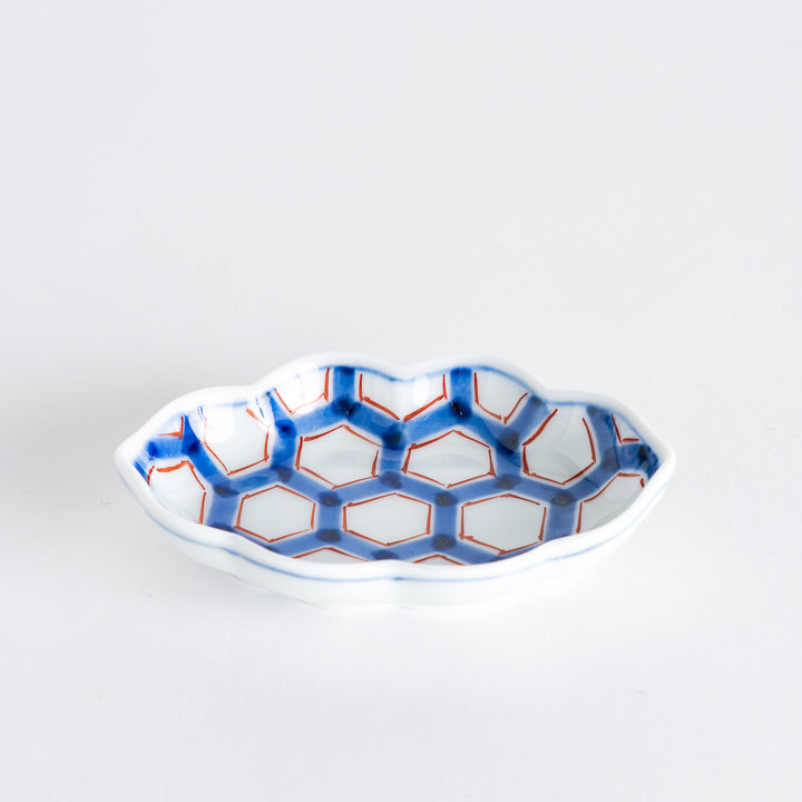 Side view of a decorative sauce dish displaying its elegant shape and intricate blue and red hexagonal pattern.