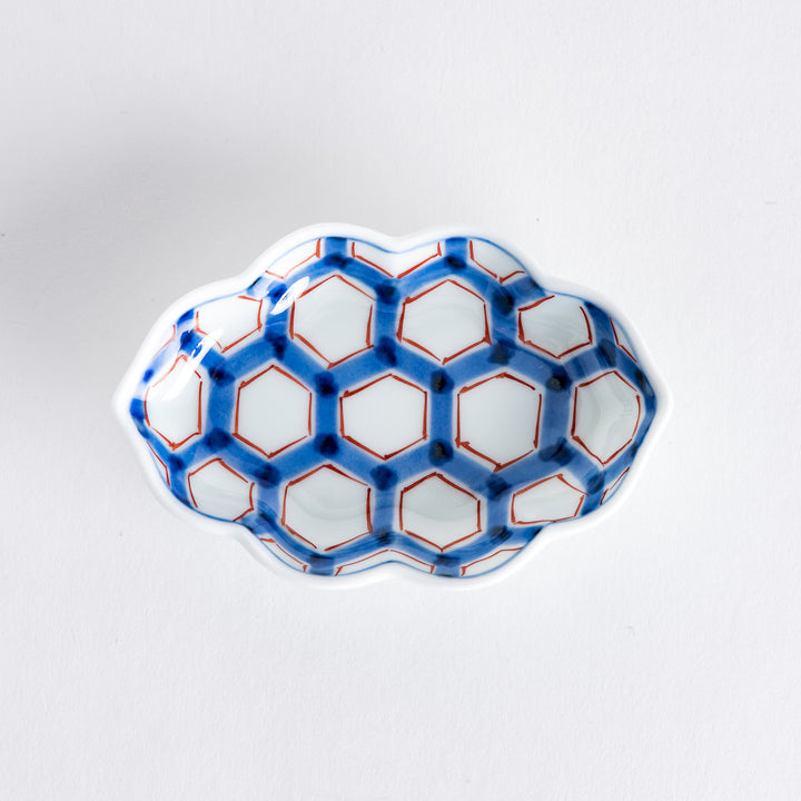 Top view of a decorative sauce dish featuring a blue and red hexagonal pattern against a white background.