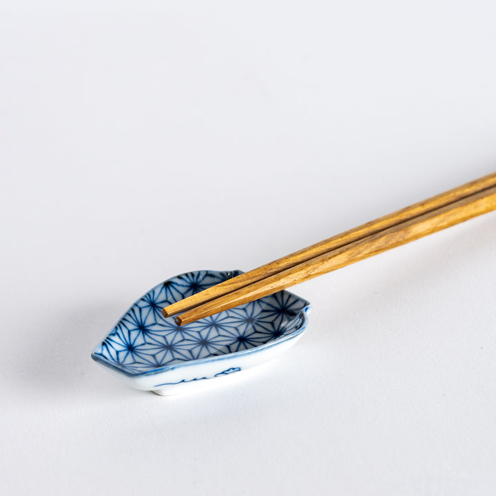 A mini sauce dish with a geometric flower pattern in blue, shaped like a vase. Paired with a set of wooden chopsticks for an elegant presentation.