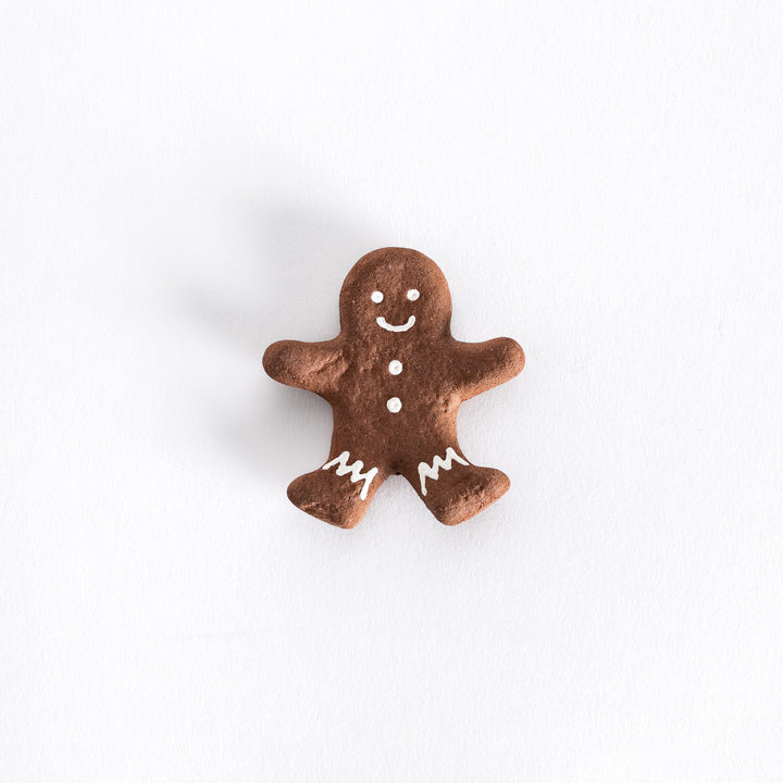 A  festive gingerbread man-shaped chopstick rest with a smiling face, white icing details on the arms, legs, and buttons.