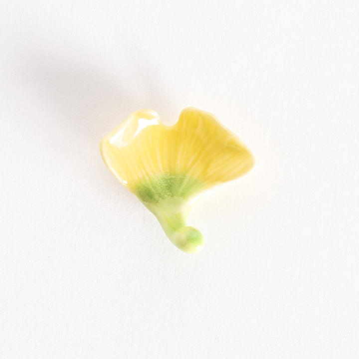 Ginkgo-shaped yellow chopsticks rest with a green stem.