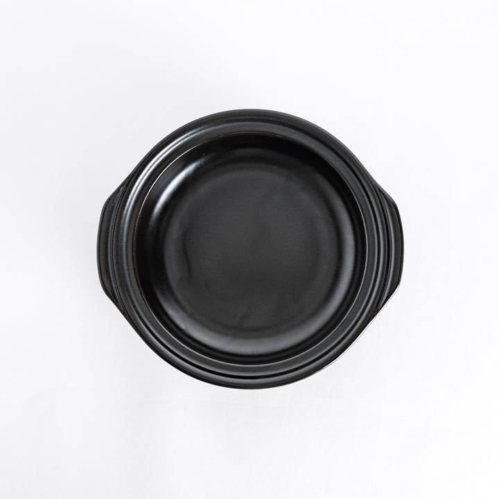 Top-down view of a blue donabe pot with the lid removed, showcasing the black interior.