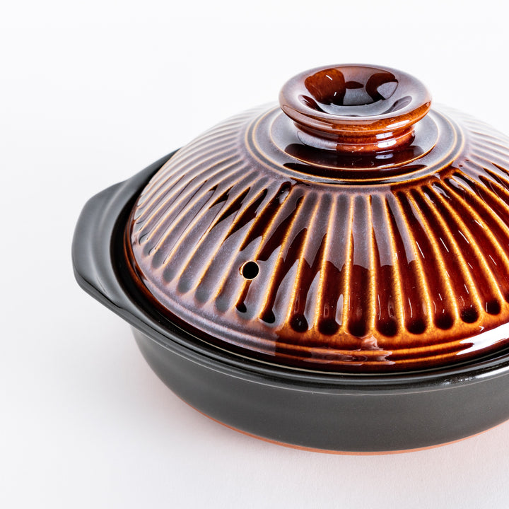 Close-up of a brown donabe pot, focusing on the ribbed lid's rich glaze and detailed texture.