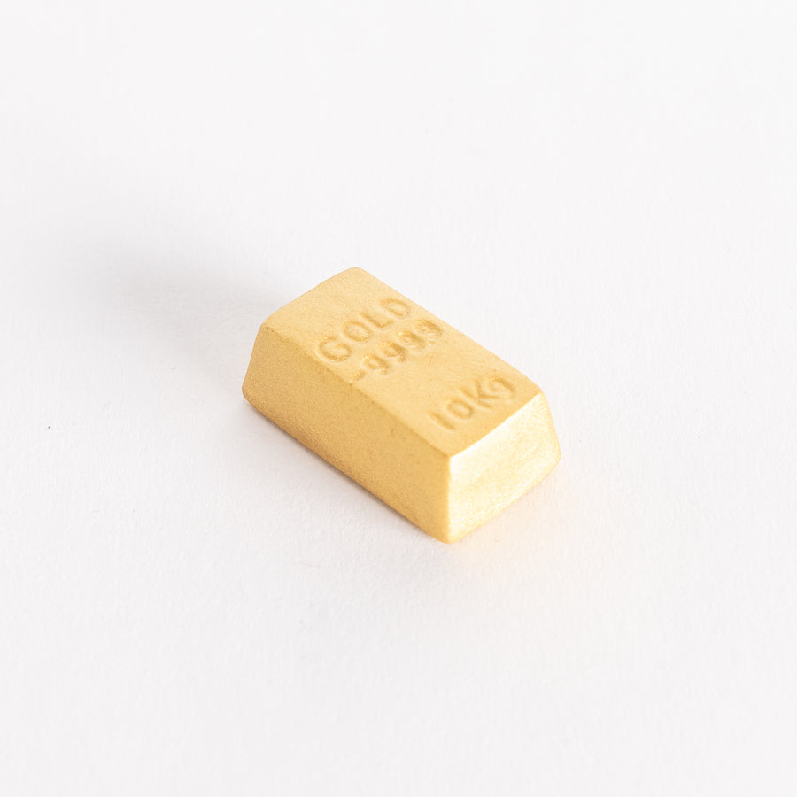 A gold bar-shaped ceramic chopstick rest with "GOLD 999.9" and "10KG" embossed on the top.