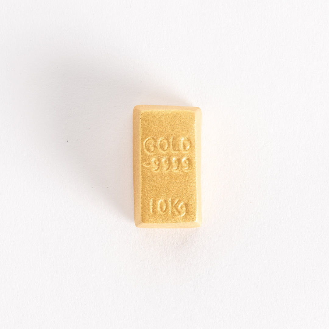 A front-facing view of the gold bar-shaped chopstick rest, showcasing the embossed text and rectangular design.