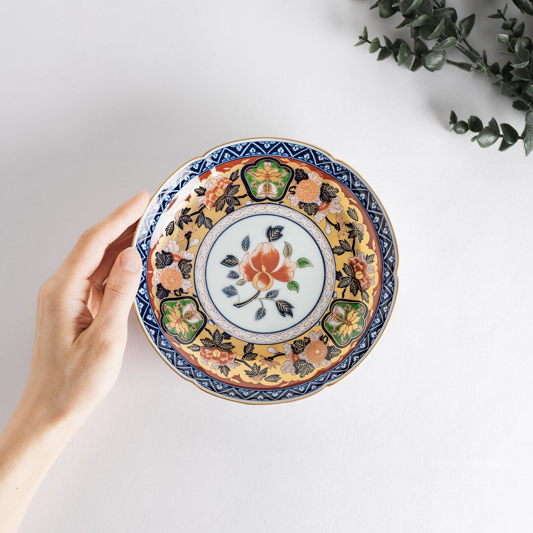 A floral salad plate with intricate gold detailing, showcasing a vibrant red flower at its center surrounded by intricate patterns in green, blue, and gold.