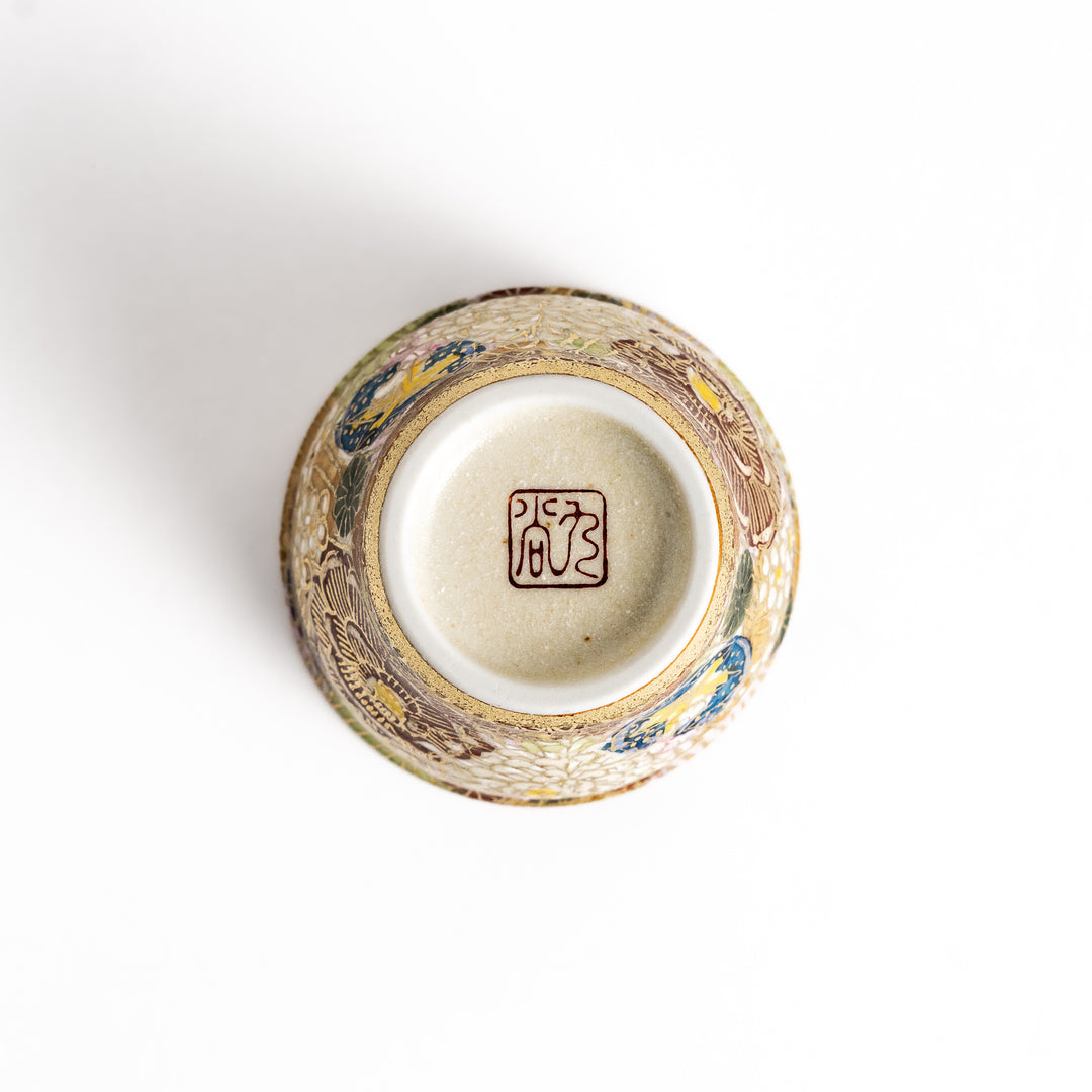 Elegant sake cup with a vibrant floral pattern in gold and pastel colors, perfect for savoring the delicate flavors of sake in style.