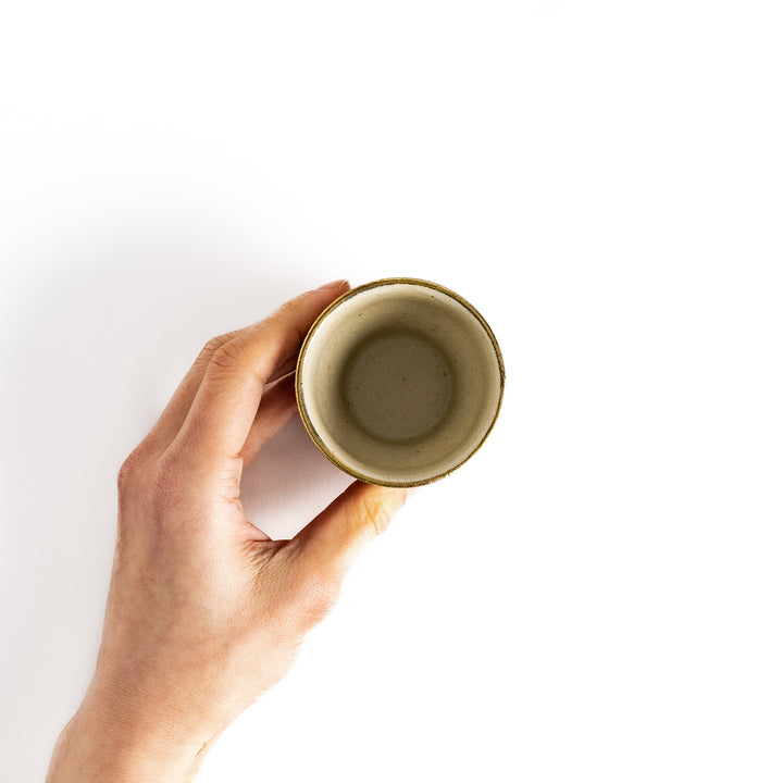 Hand holding a sake cup with a gold rim, viewed from above, perfect for enjoying a sip of sake.