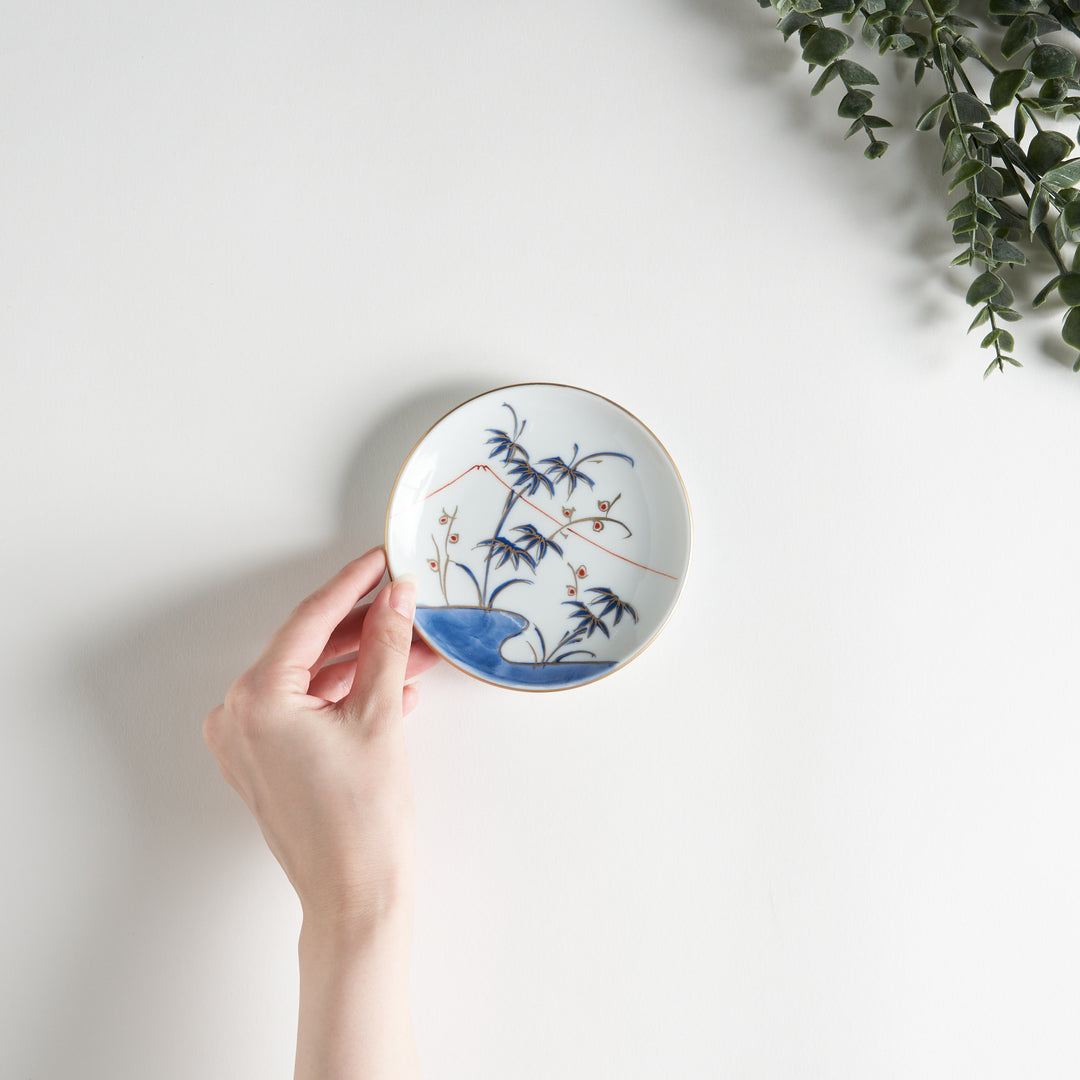 Round plate with a blue and red landscape and bamboo Mount Fuji design.