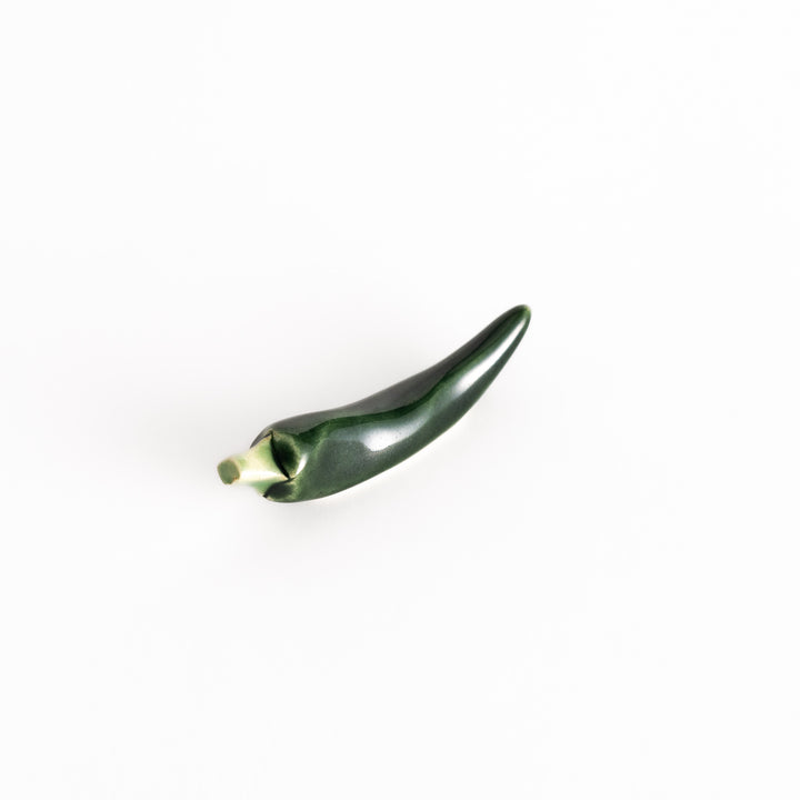 Ceramic green chili pepper-shaped chopsticks rest, showcasing its glossy finish and lifelike design.