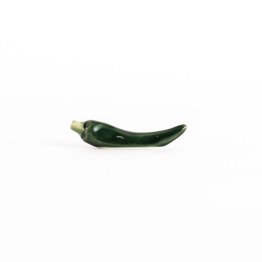 Side view of the green chili pepper chopsticks rest, capturing its curved design and vibrant green color.