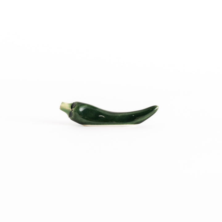 Side view of the green chili pepper chopsticks rest, capturing its curved design and vibrant green color.