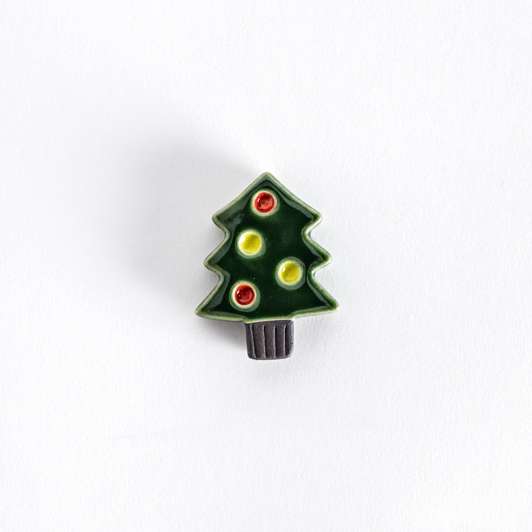 A ceramic chopsticks rest shaped like a green Christmas tree with red and yellow ornaments.