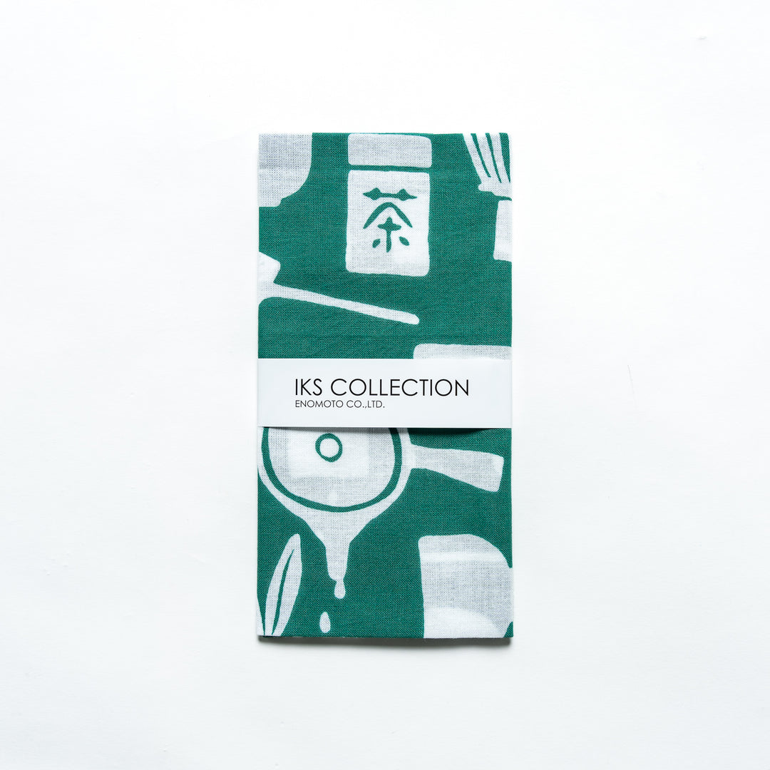 Dark green tenugui hand towel folded with a visible product sleeve, showcasing its tea-themed design.