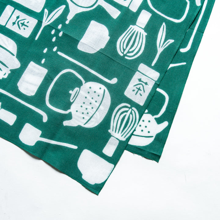 Close-up of the white tea-themed design on the dark green tenugui hand towel, highlighting detailed motifs.