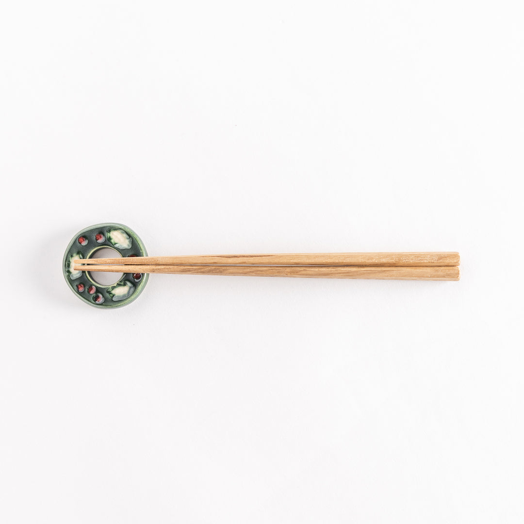 A wide view of the green wreath-shaped chopstick rest holding chopsticks, showcasing its intricate festive design.