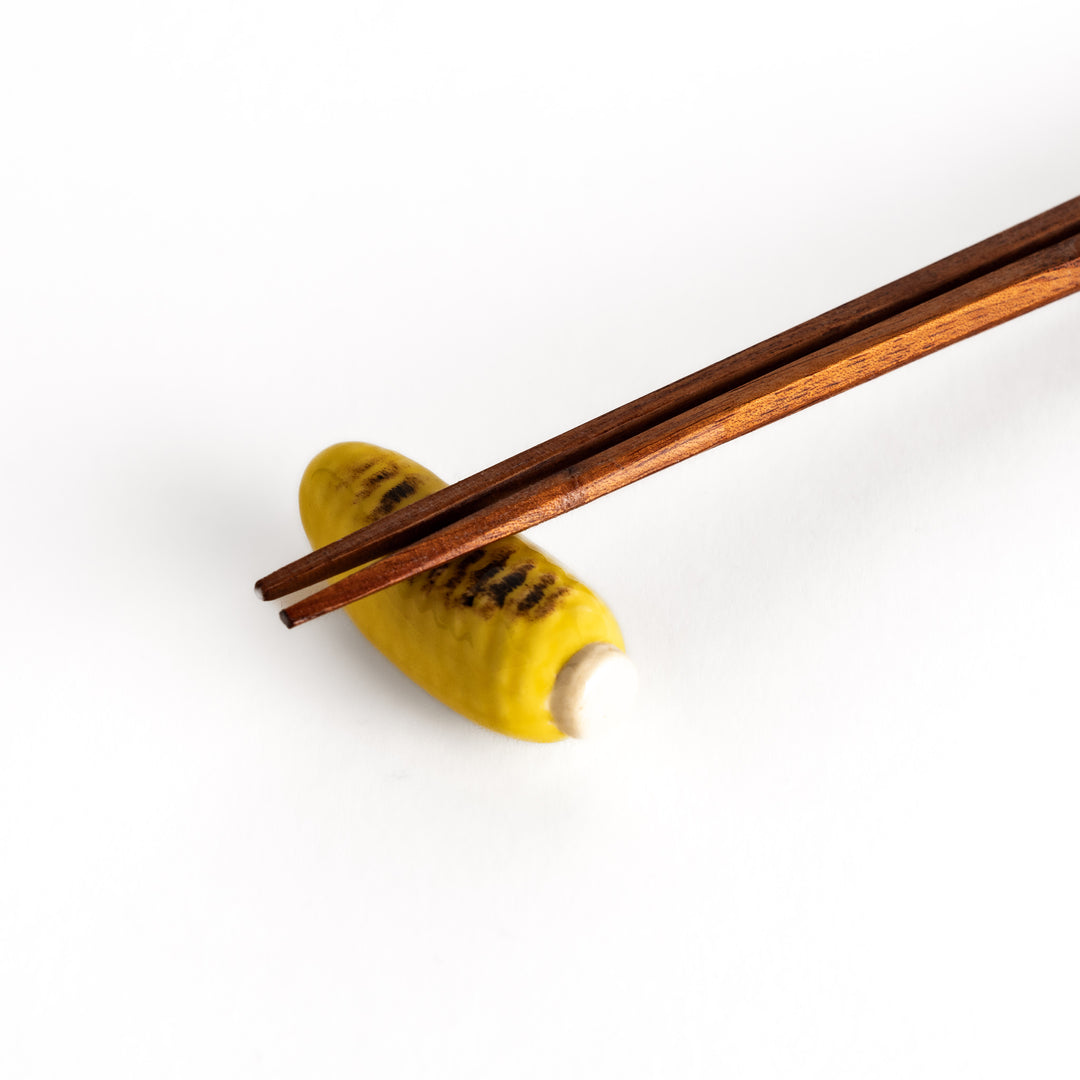 Close-up view of chopsticks placed on the grilled corn chopsticks rest, emphasizing the intricate grilled texture and glossy finish.