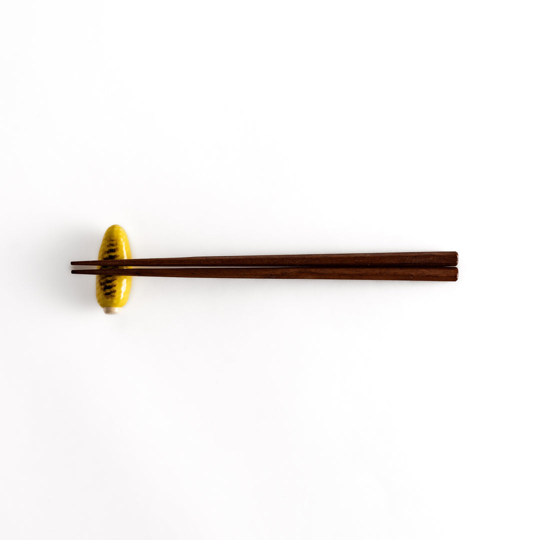 Distant view of chopsticks resting on the grilled corn chopsticks rest, highlighting its vibrant yellow color and detailed char marks.