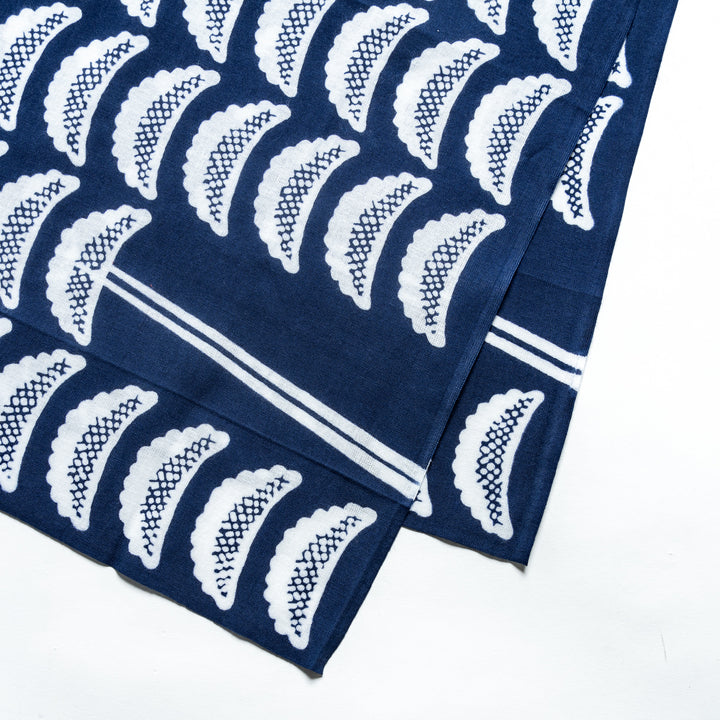 Close-up view of the tenugui's white gyoza patterns on a navy blue background, highlighting the intricate details of the design.