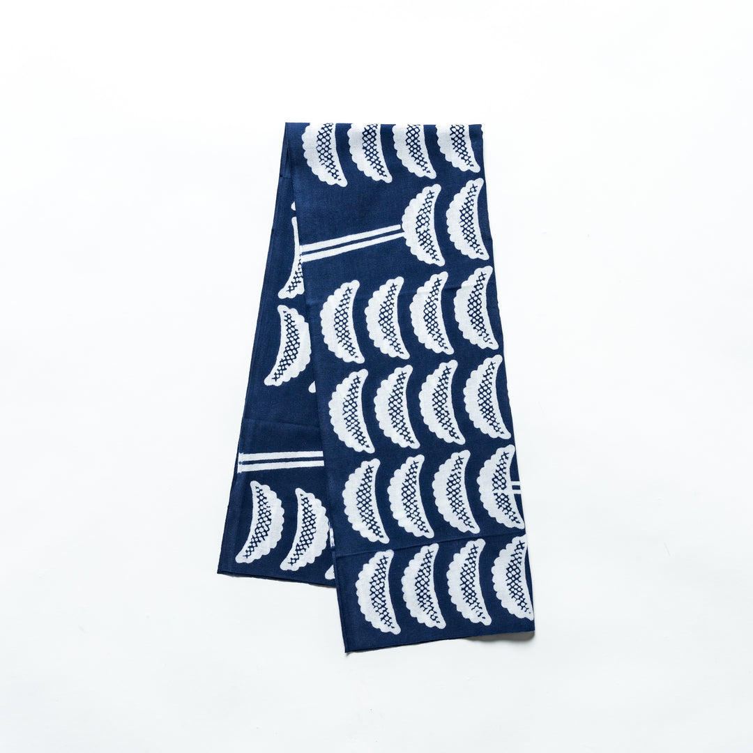 Tenugui with a navy blue base featuring repeating white gyoza patterns, neatly folded and placed on a white background.