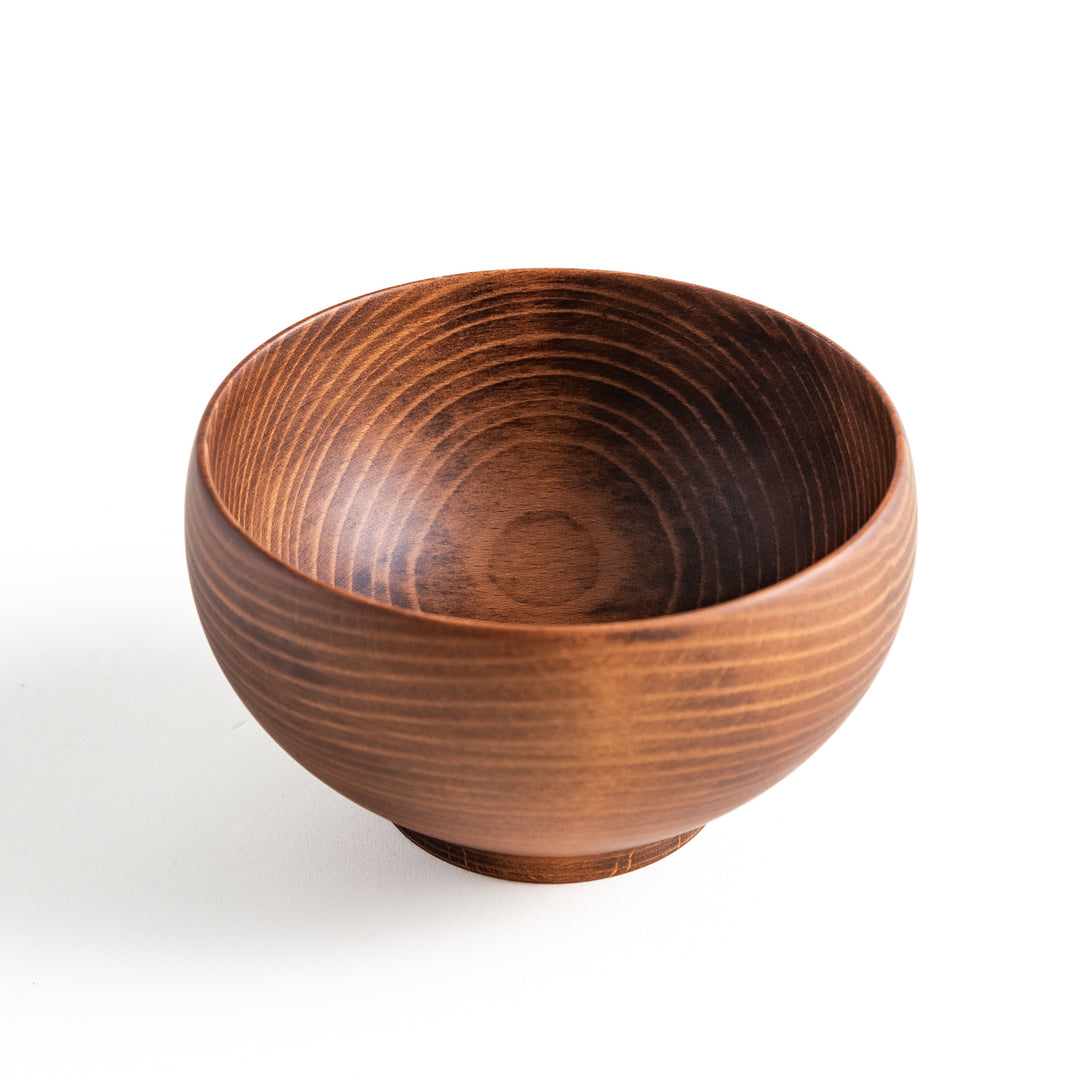 Close-up of a dark wooden bowl, highlighting its rounded shape and beautiful wood grain, ideal for soups or snacks.