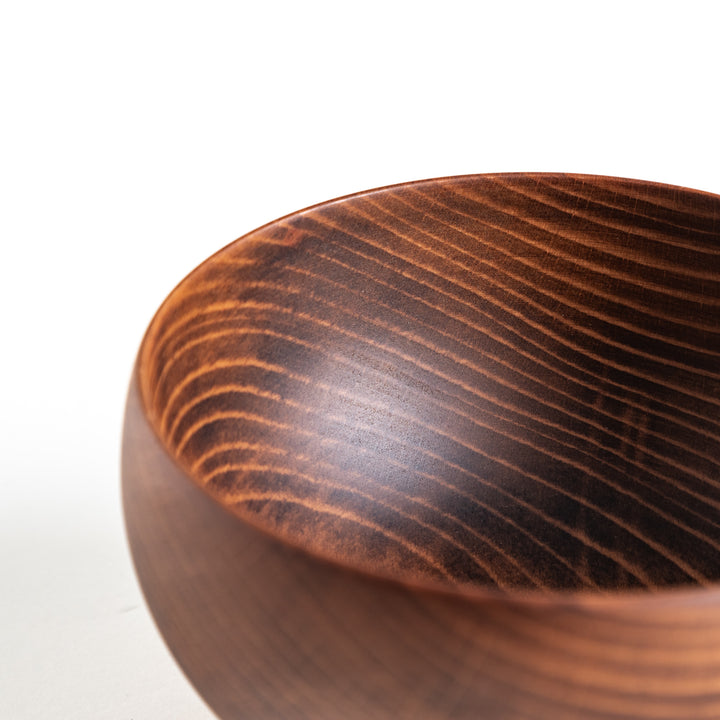 Angled view of a dark wooden bowl, emphasizing its rich color and smooth finish, great for dining presentations.