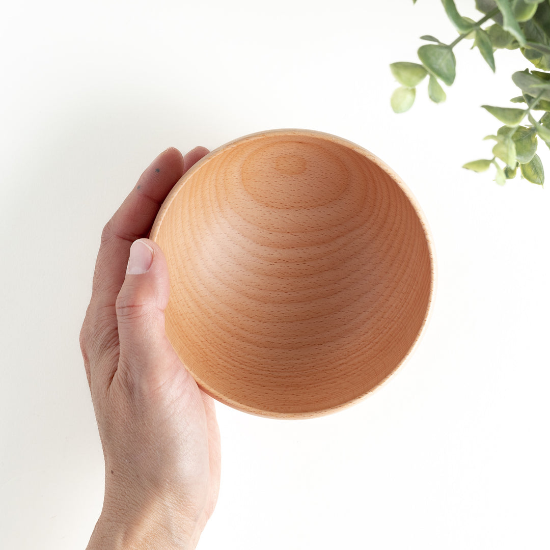 Handheld view of a handcrafted beech wood bowl, highlighting its simple elegance. Perfect for everyday dining needs.