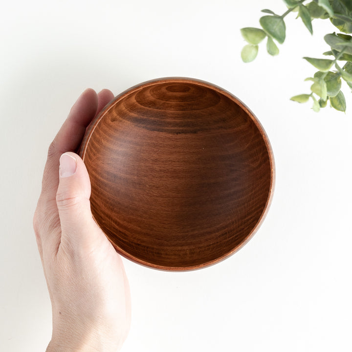 Handheld view of the interior of a beechwood bowl, highlighting its fine texture and polished finish.