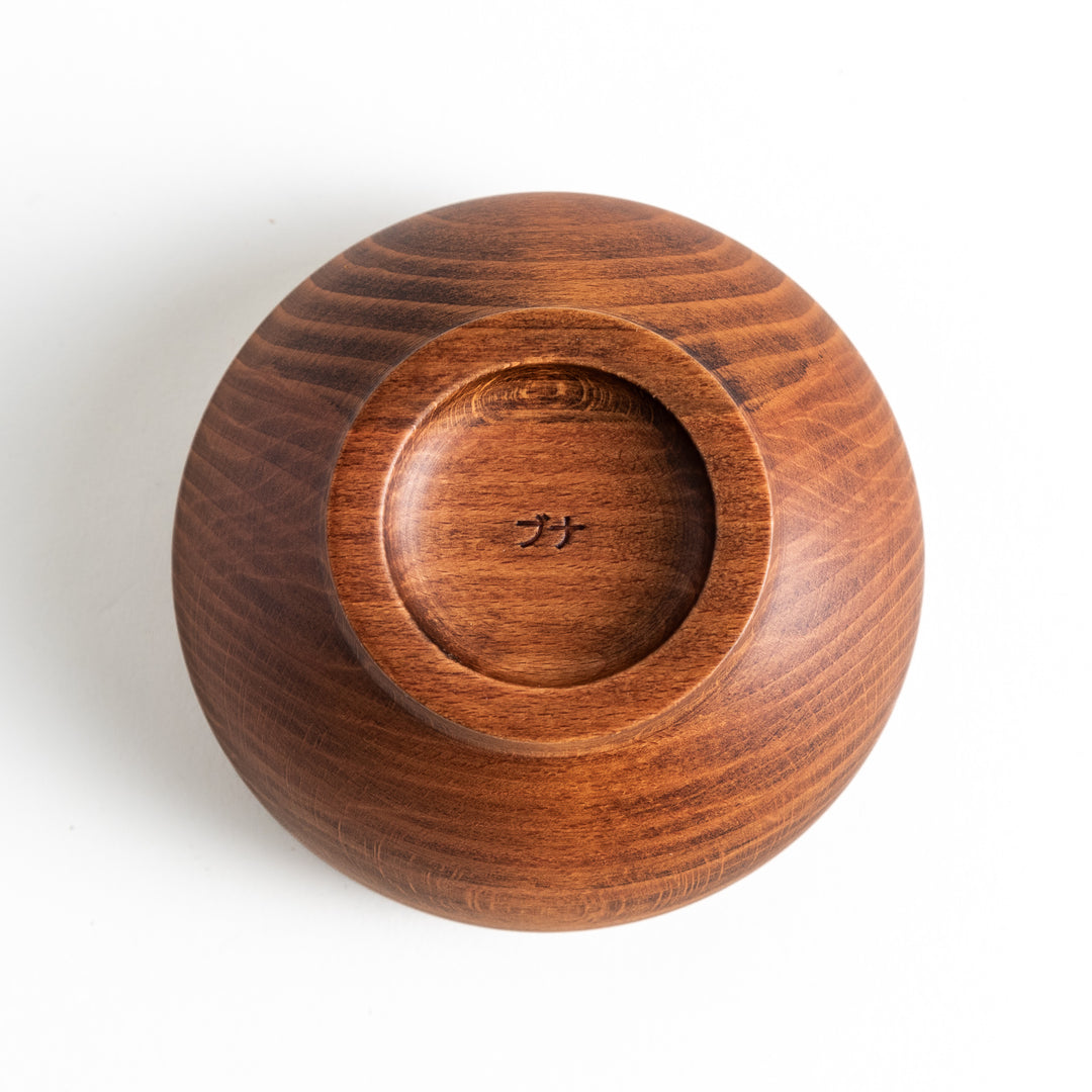 The base of the beechwood bowl, displaying the unique wood grain and craftsmanship with a small engraving.