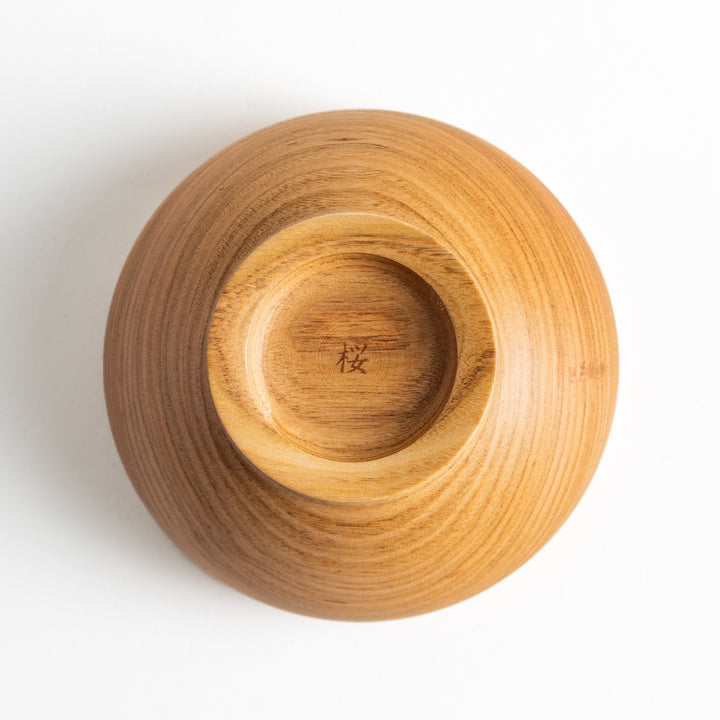 Bottom of the cherry wood bowl with Japanese characters engraved, highlighting the artisanal craftsmanship and attention to detail.