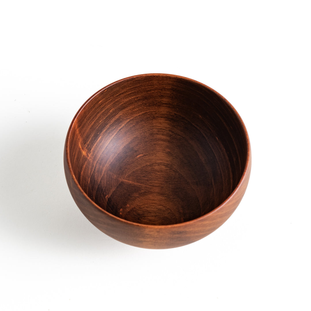 Top-down view of the dark brown cherry wood bowl, revealing a circular grain pattern in the interior.